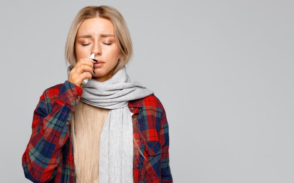 mulher com sintomas de rinite alérgica, utilizando spray intransal de avamys (fluticasona)